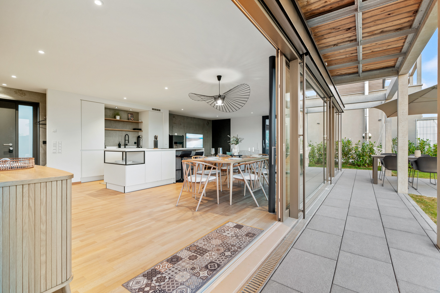 Offener Wohn- und Essbereich mit geöffneter Glasfront zum Garten