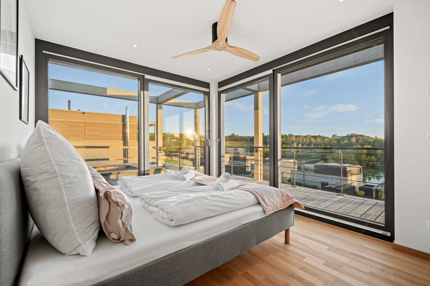 Masterbedroom im OG mit Doppelbett und großer Fensterfront über Eck zum See